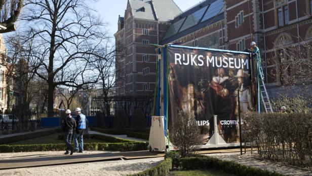 Arbeiter installieren eine große Werbetafel für das Rijksmuseum.
