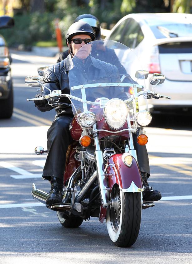 Arnold Schwarzenegger fährt auf einem roten Indian-Motorrad.