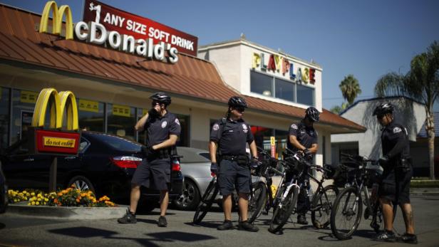 Mehrere Polizisten mit Fahrrädern stehen vor einem McDonald's Restaurant.