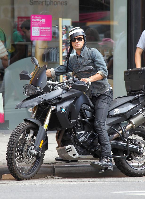 Ein Mann mit Helm und Sonnenbrille sitzt auf einem schwarzen BMW-Motorrad.