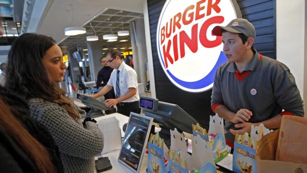 Eine Kundin bestellt bei einem Burger King Mitarbeiter.