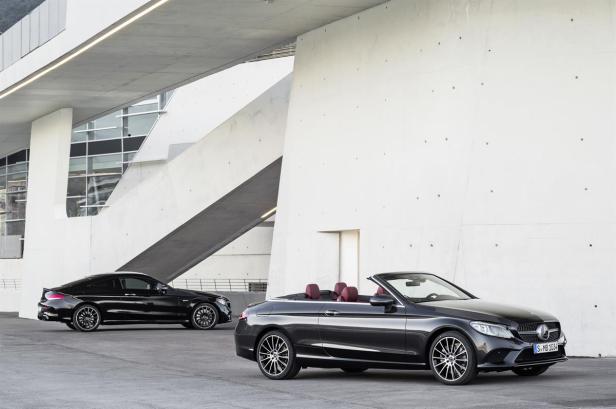 Ein schwarzes Mercedes-Benz Cabriolet und ein Coupé stehen vor einem modernen Gebäude.