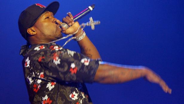 50 Cent rappt mit einem Mikrofon in der Hand auf einer Bühne.