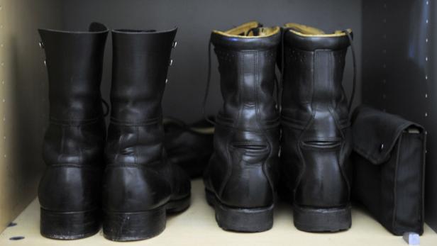 Zwei Paar schwarze Lederstiefel stehen auf einem Regal.