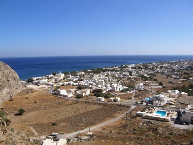 Luftaufnahme einer griechischen Stadt mit weiß getünchten Häusern am Meer.