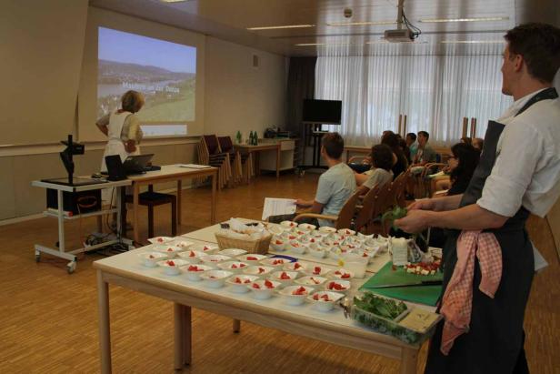 Ein Koch bereitet in einem Seminarraum Speisen für die Teilnehmer vor.