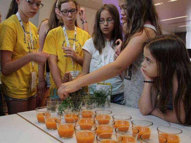 Eine Gruppe Mädchen bereitet Getränke mit Kräutern zu.