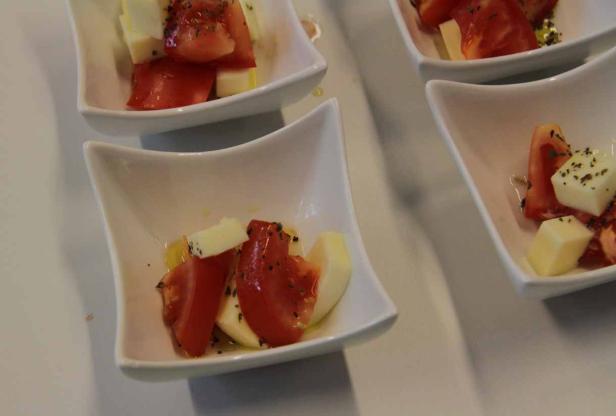 Kleine Schalen mit Tomaten, Mozzarella und Kräutern als Vorspeise.