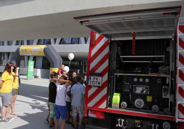 Eine Gruppe von Kindern steht vor einem geöffneten Feuerwehrwagen.