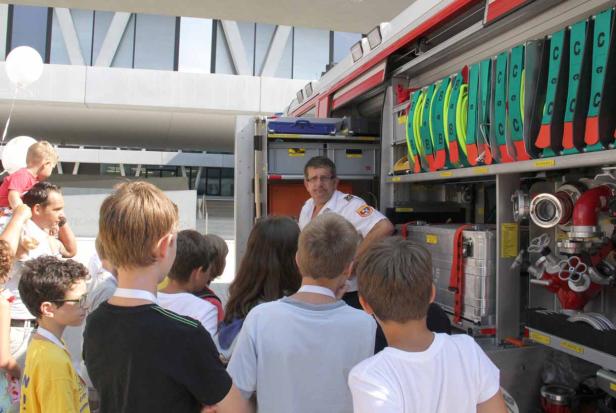 Eine Gruppe von Kindern sieht sich ein offenes Feuerwehrauto an.
