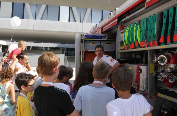 Ein Feuerwehrmann erklärt Kindern die Ausrüstung eines Feuerwehrautos.