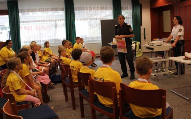 Polizisten informieren eine Gruppe von Kindern in gelben T-Shirts.