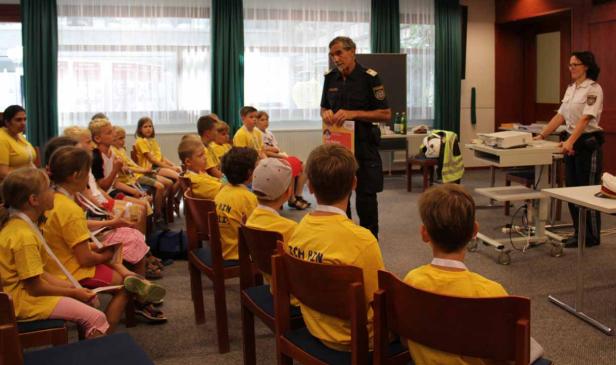 Polizisten informieren eine Gruppe von Kindern in gelben T-Shirts.