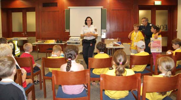 Eine Polizistin hält einen Vortrag vor einer Gruppe von Kindern.
