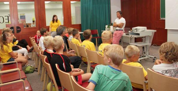 Ein Mann hält einen Vortrag vor einer Gruppe von Kindern.