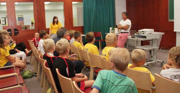 Ein Mann hält einen Vortrag vor einer Gruppe von Kindern in einem Raum.