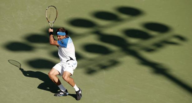 Ein Tennisspieler schlägt den Ball auf einem Tennisplatz.