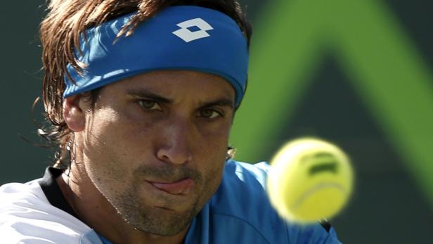 Ein Tennisspieler mit blauem Stirnband schaut auf einen Tennisball.