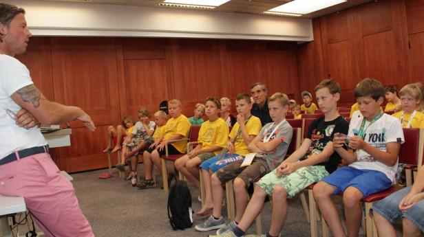 Ein Mann hält einen Vortrag vor einer Gruppe von Kindern in einem Raum.