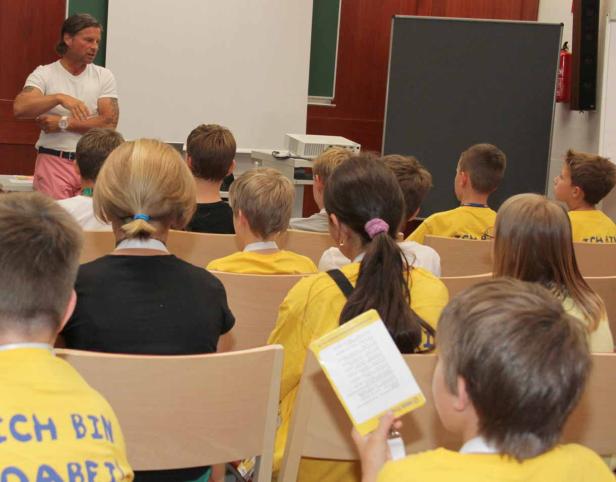 Ein Mann hält vor einer Gruppe von Kindern einen Vortrag.