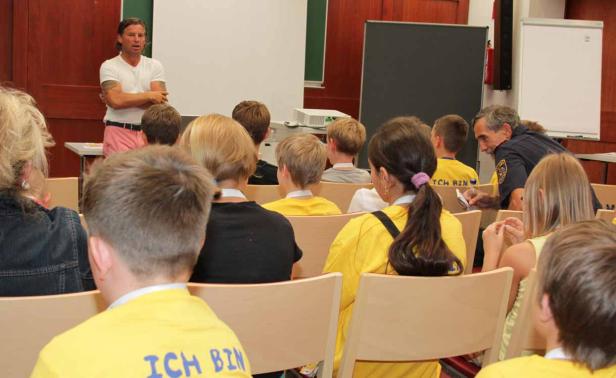 Ein Mann hält einen Vortrag vor einer Gruppe von Kindern.