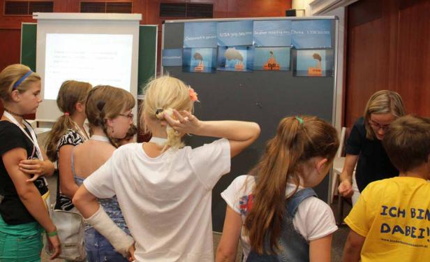 Eine Gruppe Kinder betrachtet eine Präsentation über CO2-Emissionen verschiedener Länder.