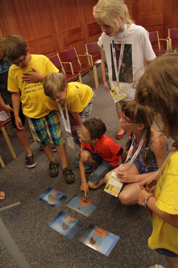 Eine Gruppe Kinder spielt ein Spiel mit Bildkarten auf dem Boden.