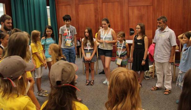 Eine Gruppe von Kindern und ein Mann stehen in einem Kreis in einem Raum.