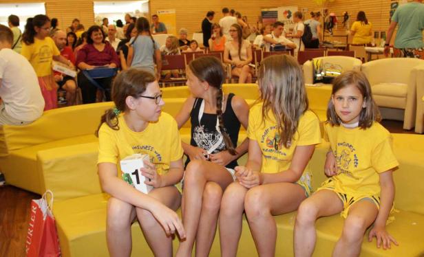 Vier Mädchen sitzen auf einer gelben Bank und tragen gelbe T-Shirts.