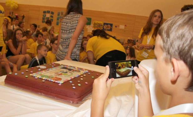 Ein Junge fotografiert mit seinem Smartphone eine große, dekorierte Torte.