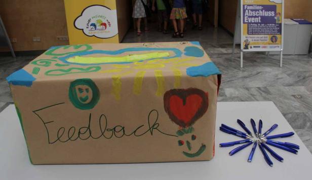 Eine bemalte Feedback-Box steht neben einem Arrangement aus blauen Stiften.