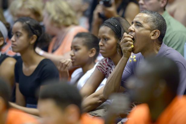 Barack Obama isst Popcorn mit seiner Familie bei einem Basketballspiel.