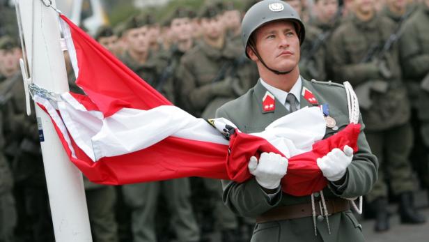 Ein österreichischer Soldat in Uniform hält die österreichische Flagge.