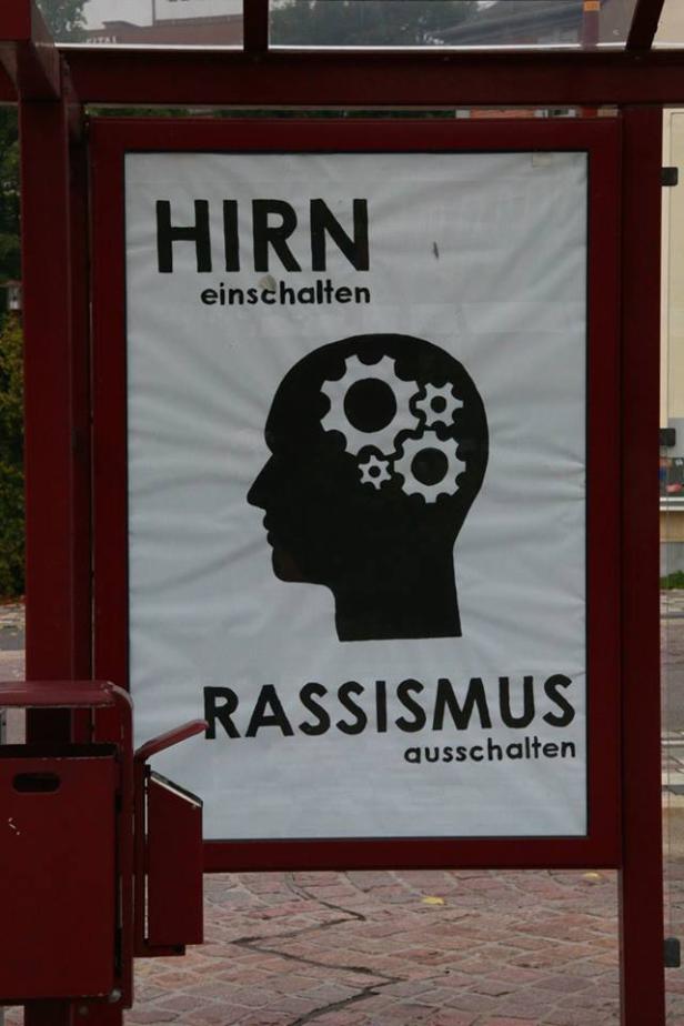 Ein Plakat fordert dazu auf, das Hirn einzuschalten und Rassismus auszuschalten.