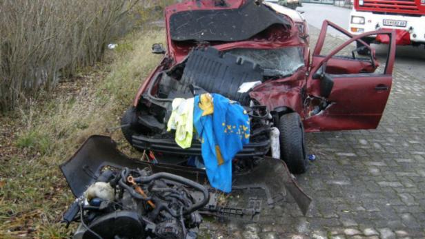 Ein rotes Auto ist nach einem Unfall stark beschädigt.
