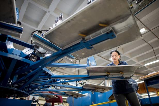 Eine Frau arbeitet an einer Siebdruckmaschine in einer Fabrik.