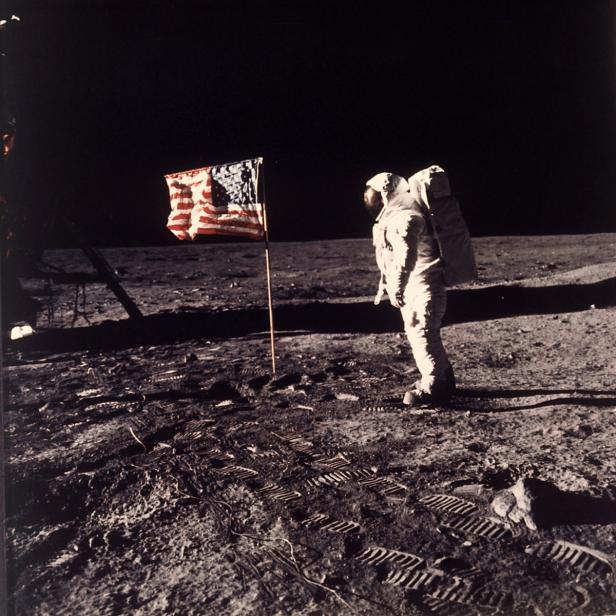 Ein Astronaut steht neben einer US-Flagge auf der Mondoberfläche.