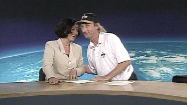 Eine Frau und ein Mann stehen an einem Tisch vor einer Weltraumkulisse.
