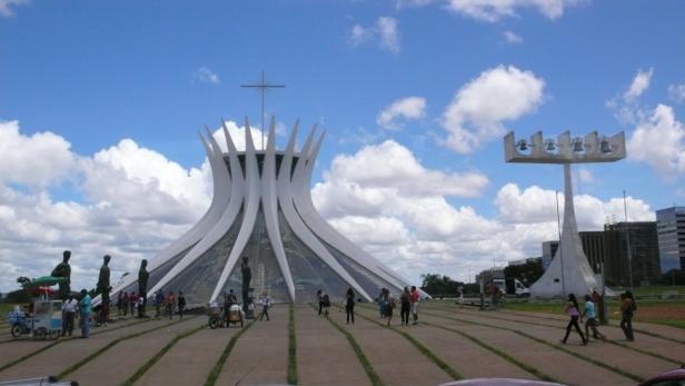 Die Kathedrale von Brasília und der Glockenturm vor blauem Himmel mit Wolken.
