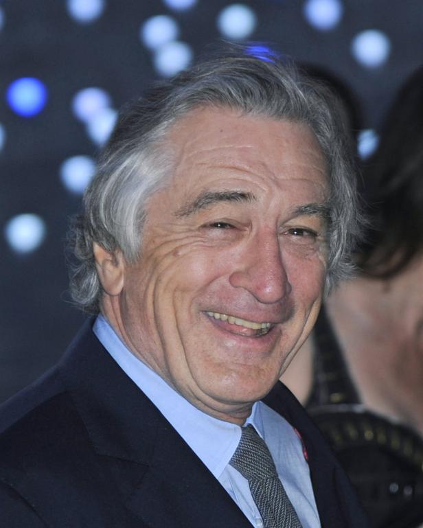 Porträt von Robert De Niro, der in einem dunklen Anzug lächelt.