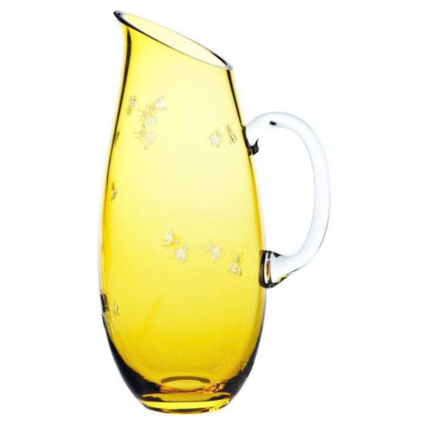 Ein gelber Glaskrug mit weißen Bienenmotiven und einem transparenten Griff.
