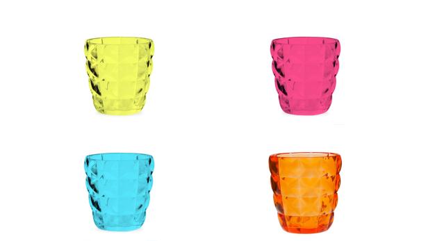 Vier bunte, facettierte Trinkgläser in Gelb, Pink, Türkis und Orange vor einem weißen Hintergrund.