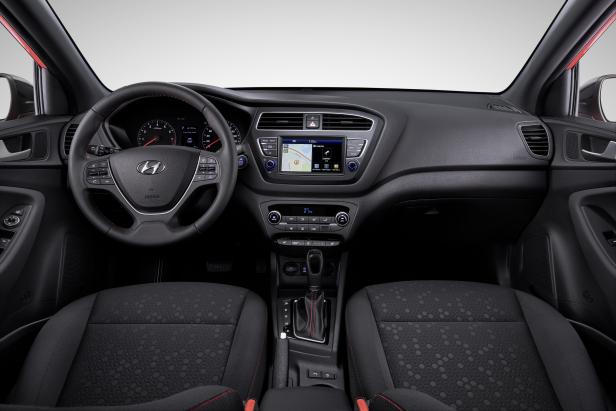 Innenraum eines Autos mit schwarzem Armaturenbrett und Sitzen mit roten Akzenten.