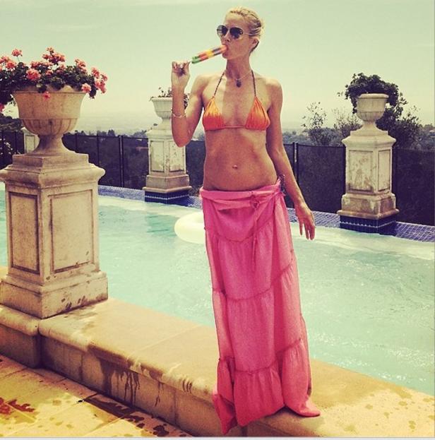 Eine Frau in Bikini und Rock isst ein Eis am Pool.