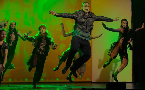 Eine Gruppe von Tänzern tritt in Kostümen auf einer Bühne auf.