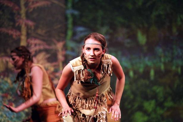 Eine junge Frau in einem indigenen Kostüm auf einer Bühne.