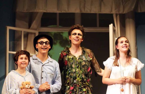 Eine Aufführung von „Peter Pan“ mit vier jungen Schauspielern auf der Bühne.