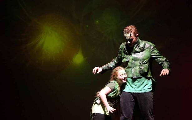 Zwei Schauspieler in grünen Kostümen stehen auf einer Bühne.