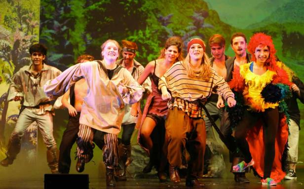 Eine Gruppe von Schauspielern in Kostümen steht auf einer Bühne vor einer Dschungelkulisse.