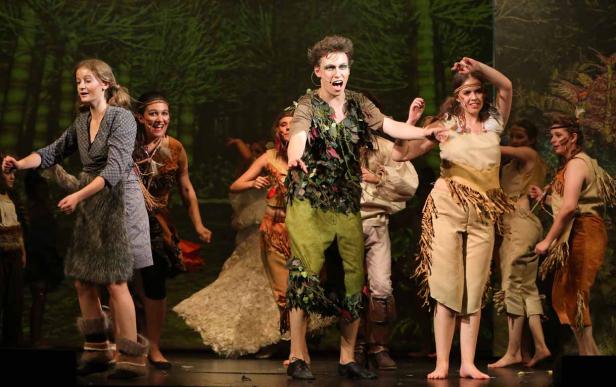 Eine Gruppe von Schauspielern in Kostümen steht auf einer Bühne vor einem Waldhintergrund.